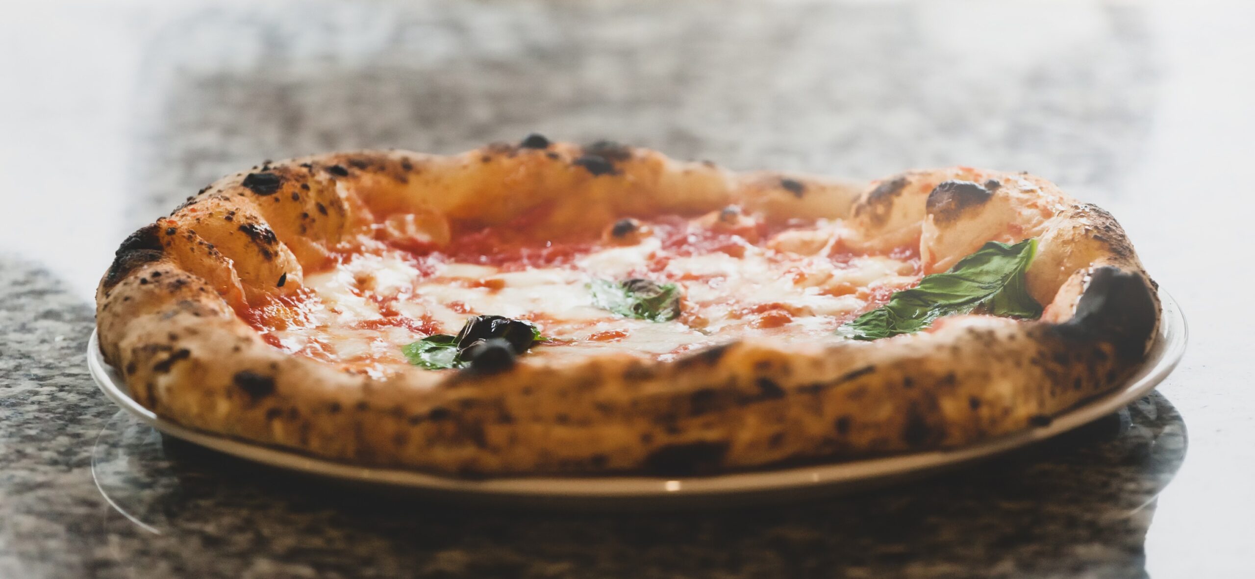 Selective focus of margherita pizza in plate on marble top.